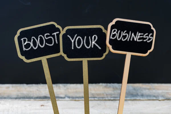BOOST YOUR BUSINESS message written with chalk on wooden mini blackboard labels