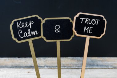 Mini tahta etiketleri üzerinde tebeşirle yazılmış Sakin ve Güven Me mesajı tutun