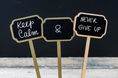 Mini tahta etiketleri üzerinde tebeşirle yazılmış Sakin ve Asla Vazgeçmem mesajı tutun