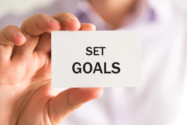 Empresario sosteniendo una tarjeta con texto SET GOALS —  Fotos de Stock