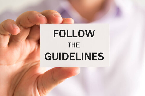 Businessman holding FOLLOW THE GUIDELINES card