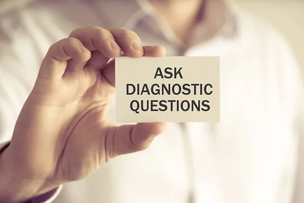 Businessman holding ASK DIAGNOSTIC QUESTIONS card
