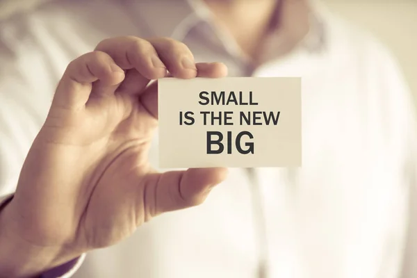 Бизнесмен, держащий SMALL - это новая большая карточка для сообщений — стоковое фото