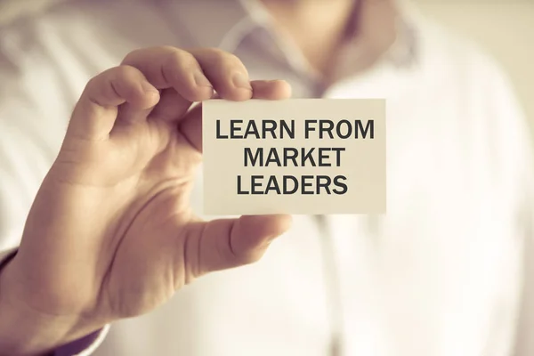 Öğrenmek dan piyasa liderleri mesaj kart tutan işadamı — Stok fotoğraf