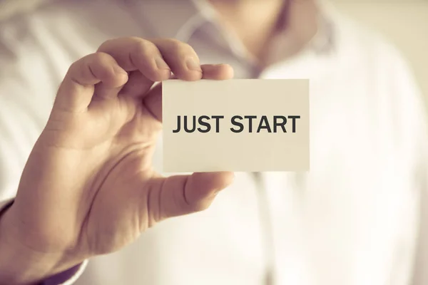 Businessman holding card with text JUST START — Stock Photo, Image