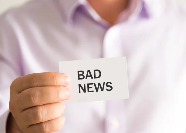 Empresário segurando um cartão com texto BAD NEWS — Fotografia de Stock