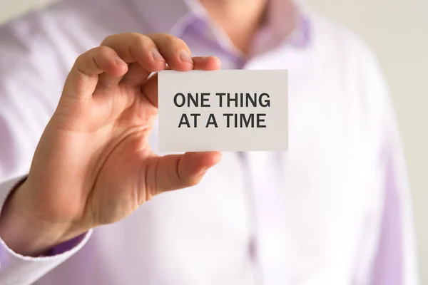 Empresário segurando um cartão com texto uma coisa em um tempo — Fotografia de Stock