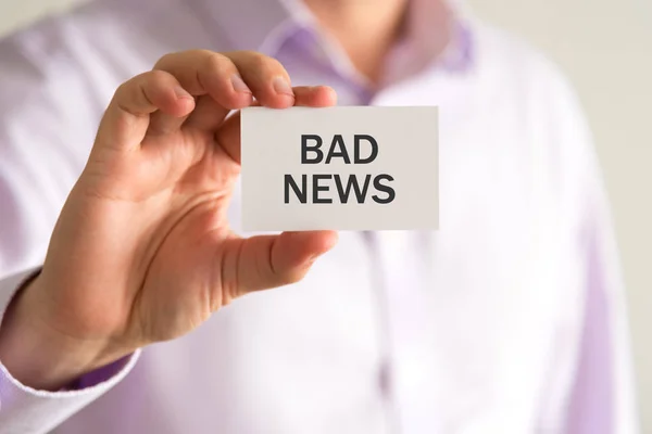 Affärsman som håller ett kort med texten dåliga nyheter — Stockfoto