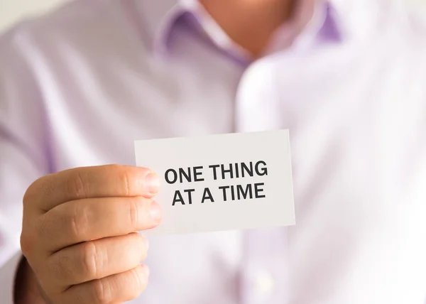 Επιχειρηματίας που κρατά μια κάρτα με το κείμενο ένα πράγμα At A Time — Φωτογραφία Αρχείου