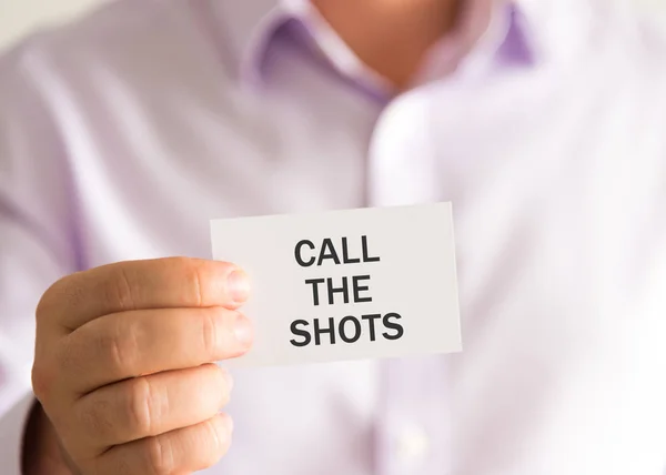 Empresario sosteniendo una tarjeta con texto LLAME THE SHOTS —  Fotos de Stock