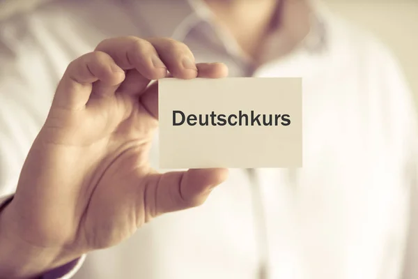 商人持消息卡"Deutschkurs"写在德语翻译︰ 德语课程 — 图库照片