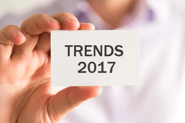 Empresário segurando um cartão com mensagem TRENDS 2017 — Fotografia de Stock