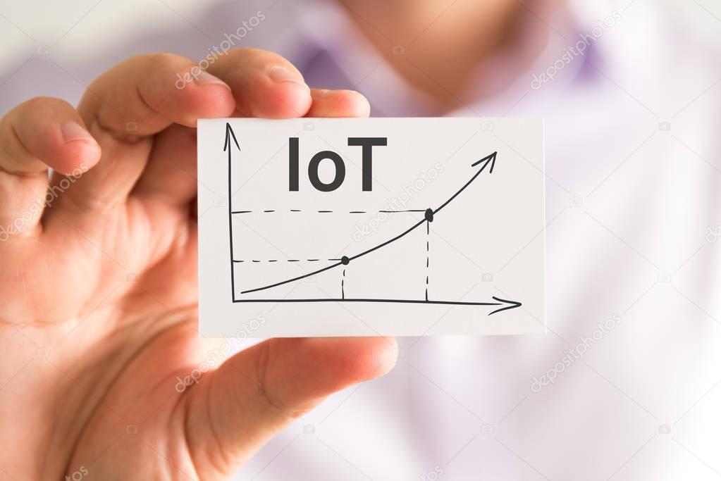 Businessman holding a card with IoT Internet Of Things rising arrow and chart
