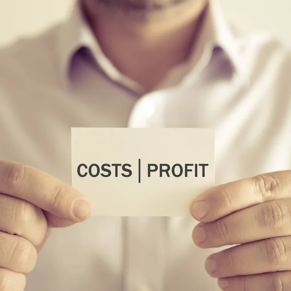 Businessman holding COSTS PROFIT message card — Stock Photo, Image