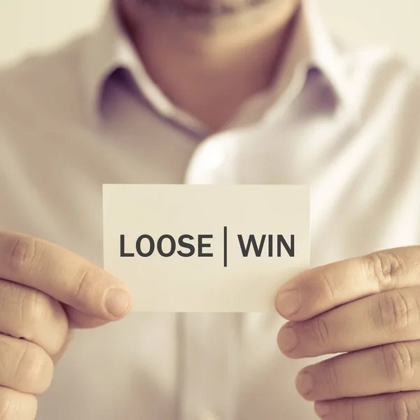 Businessman holding LOOSE WIN message card — Stock Photo, Image