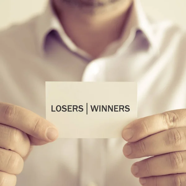Biznesmen posiadania karty wiadomość zwycięzcy przegrani — Zdjęcie stockowe