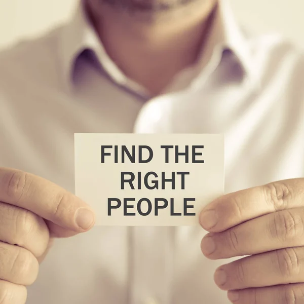 Деловой человек, держащий в руках сообщение "Найти правильных людей" — стоковое фото