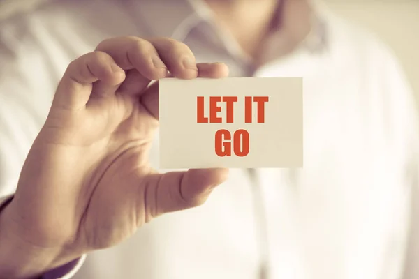 Бизнесмен, держащий в руках карточку для сообщений Let IT GO — стоковое фото
