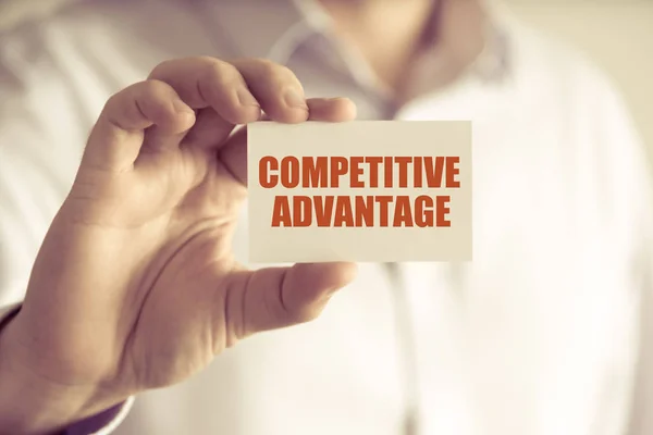 Бізнесмен тримає картку повідомлень COMPETITIVE ADVANTAGE — стокове фото