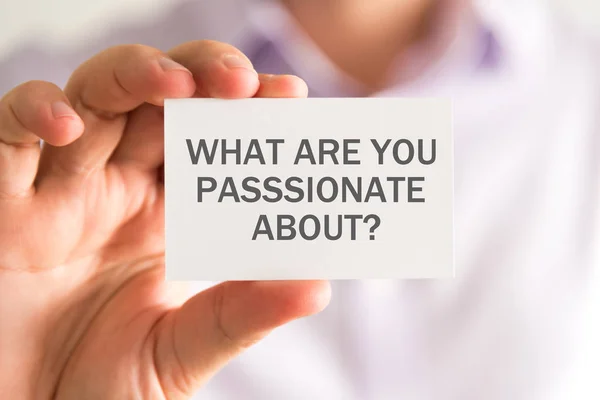 Businessman holding a card with WHAT ARE YOU PASSIONATE ABOUT ? message — Stock Photo, Image