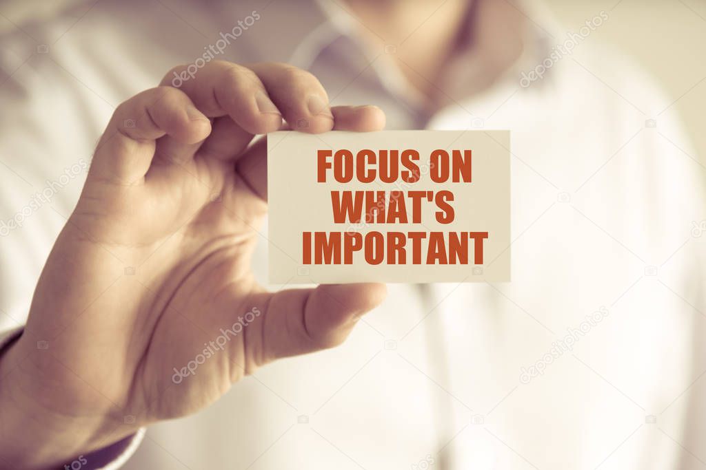 Businessman holding FOCUS ON WHATS IMPORTANT message card
