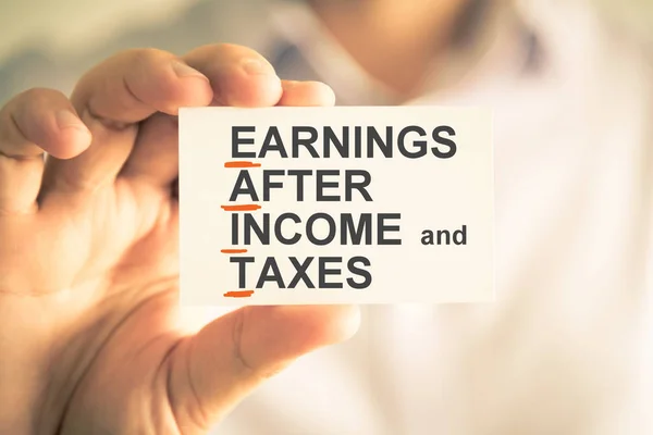 Businessman holding card with EAIT EARNINGS AFTER INCOME AND TAXES acronym text — Stock Photo, Image