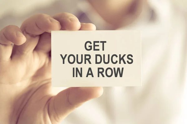 Businessman holding GET YOUR DUCKS IN A ROW message card — Stock Photo, Image