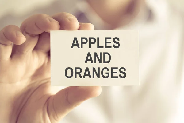 Businessman holding APPLES AND ORANGES message card — Stock Photo, Image