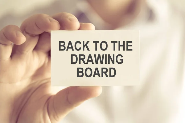 Businessman holding BACK TO THE DRAWING BOARD message card