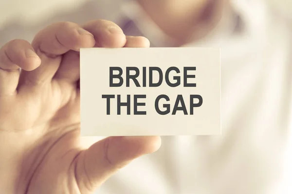 Businessman holding BRIDGE THE GAP message card — Stock Photo, Image