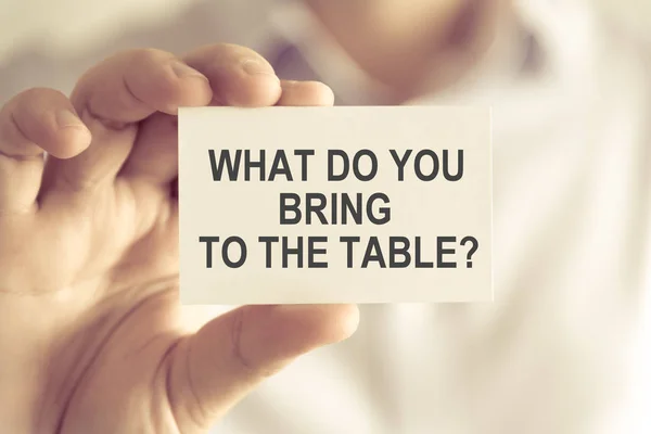 Empresario sosteniendo ¿Qué traes a la mesa? tarjeta de mensaje — Foto de Stock
