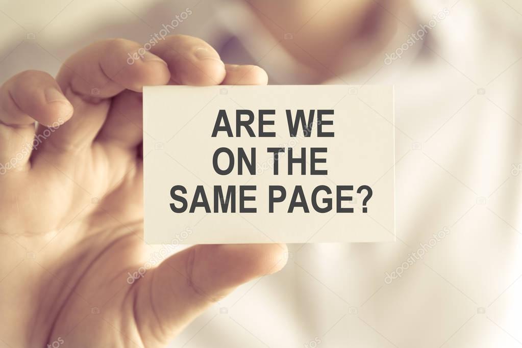 Businessman holding ARE WE ON THE SAME PAGE ? message card
