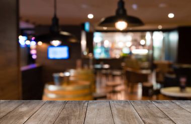 Arka plan bulanık bar sandalye ve tabloların önünde boş ahşap masa