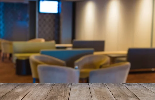 Table en bois vide devant la salle d'attente de l'hôtel avec fauteuils, fond flou avec mise au point sélective — Photo