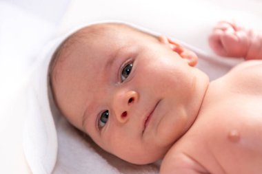 Sevimli 2 aylık küçük erkek bebek beyaz arka planda banyo üstüne havlu.