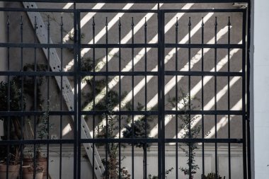 Arka planda beton duvar olan siyah demir çit. 