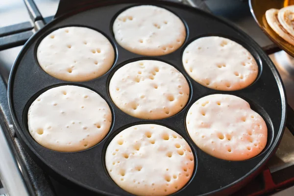 cooking pancakes in a black pan . template for the recipe. the process of cooking food