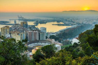 İspanya 'nın Malaga şehrinin merkezine bakın. Şehrin İspanyol Costa del Sol 'unda gün batımı, liman, evler, ağaçlar, ringler