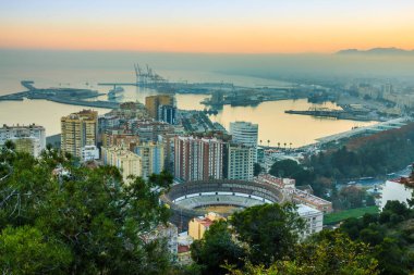 Malaga şehir merkezinin panoraması. İspanya 'nın Costa del Sol kıyı şeridinde gün batımı, liman, evler, ağaçlar ve boğa güreşi.
