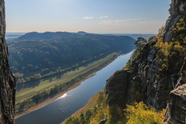 Bastei Köprüsü 'nden Sakson İsviçre' deki Elbe Vadisi 'nin Elbe Kum Taşı Dağları' nın kayalarıyla panoramik görüntüsü. Mavi gökyüzü ve sonbahar havasında bulutlarla güneşli bir gün.