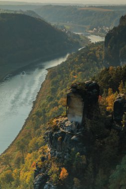River Elbe, Sakson İsviçre 'de sonbahar havasında. Taşlı kayalar ve günışığında ormanlar. Elbe Vadisi 'ndeki nehirde bir tekne. Mevsimsel renklerde ağaçlar