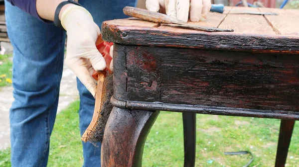 Kobieta odnawia stare meble na świeżym powietrzu. Klasyczny stół. W gumowych rękawiczkach Obraz Stockowy