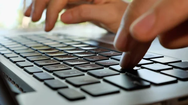 Typing hands on laptop keyboard, handheld static close up shot