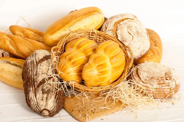 Chléb, bochníky v sortimentu na dřevěné desce — Stock fotografie