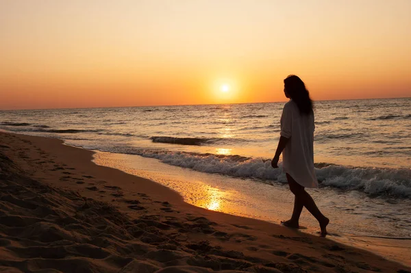 Девушка гуляет по побережью на закате, восходе солнца — стоковое фото