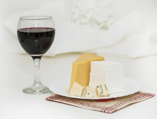 Bicchiere di vino rosso e formaggio su un piatto — Foto Stock