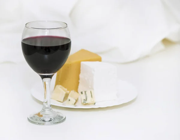 Copa de vino tinto y queso en un plato — Foto de Stock