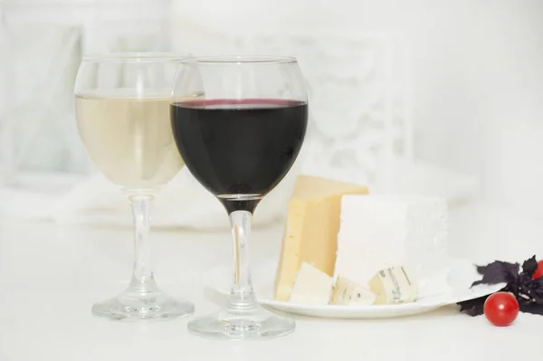 Vasos con vino tinto y blanco y queso en un plato — Foto de Stock