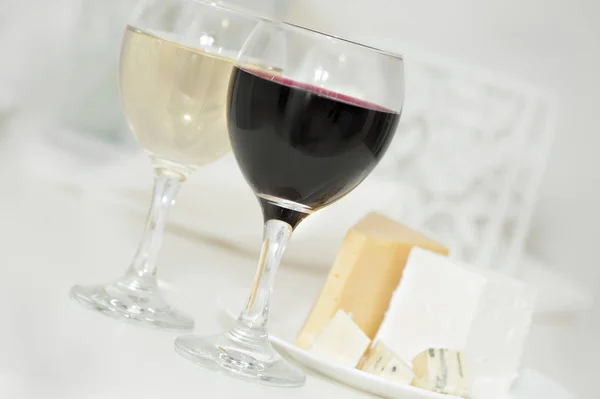 Vasos con vino tinto y blanco y queso en un plato — Foto de Stock
