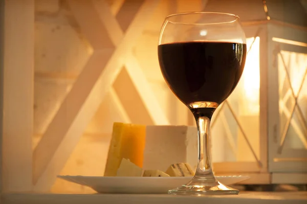 Estante con una copa de vino y un plato de queso — Foto de Stock